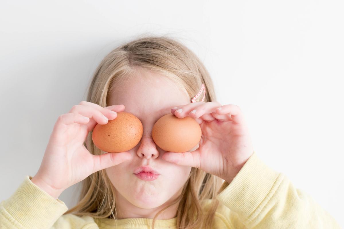 young girl holding up eggs in front of her eyes