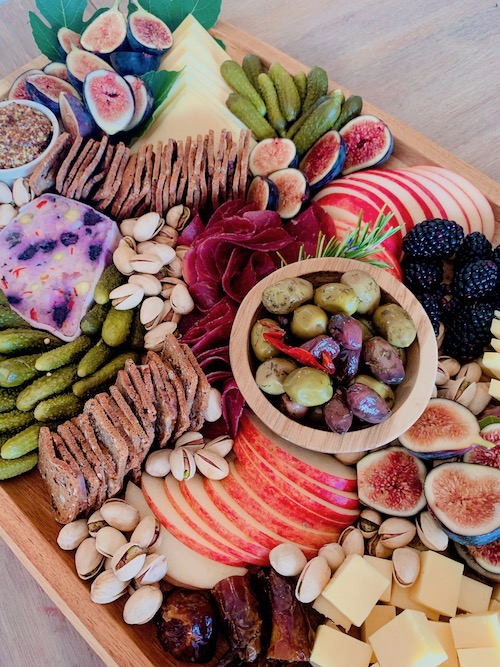 display of sliced meats, cheeses, fruits and condiments on a board